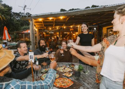 casual, relaxed scene of peopel having a toast with beer glasses in an outdoor garden bar towards the evening