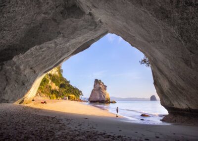 limestone arch with sandy beach and limestone formation in water in background