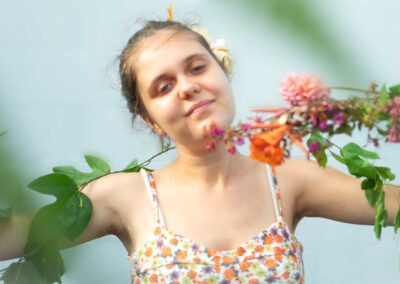 young woman in floral dress and floral items around her wirtsts