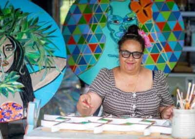 woman with thick black rimmed glasses at table being creative with colourful background